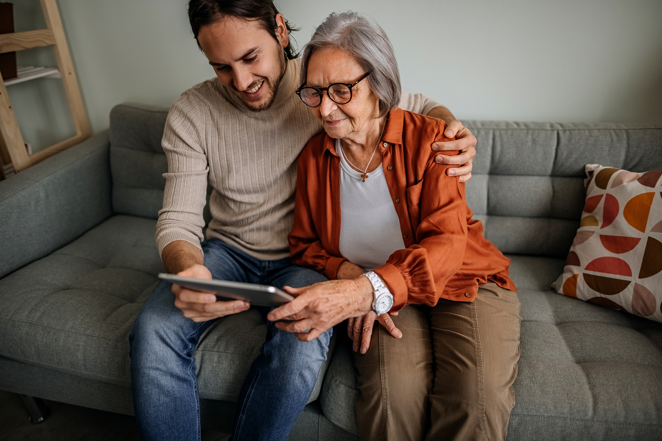 Изображение. Cын показывает пожилой маме как работает антивирус Kaspersky на планшете