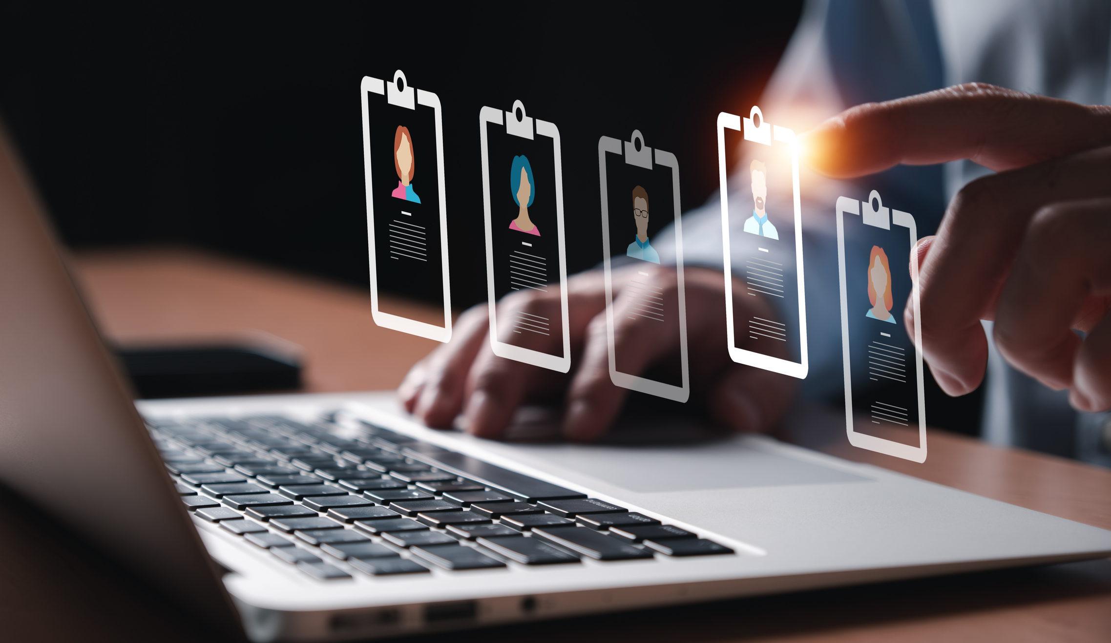 Изображение. Концепция электронного кадрового учета: бизнесмен перед ноутбуком и виртуальные карточки сотрудников