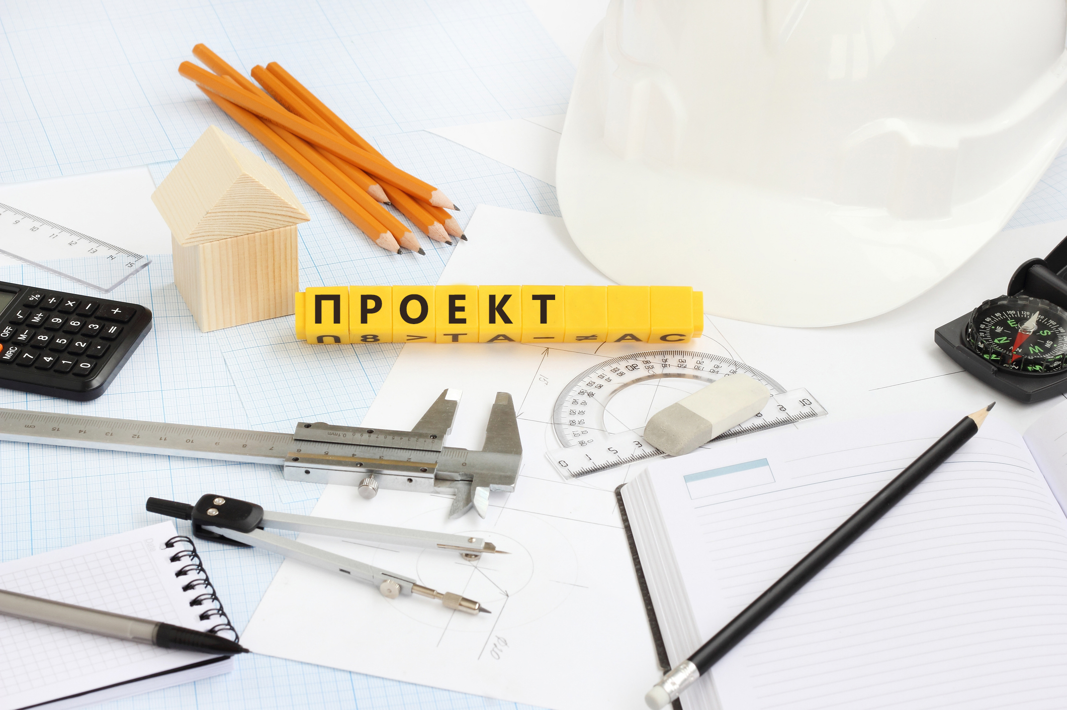 Изображение. Чертежные инструменты и каска на фоне архитектурных планов.
